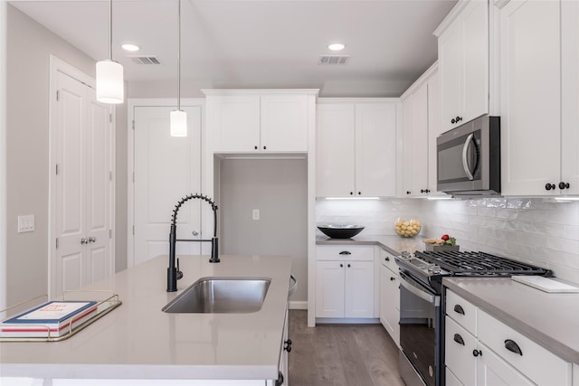 kitchen featuring stainless steel appliances, sink, pendant lighting, a center island with sink, and white cabinetry