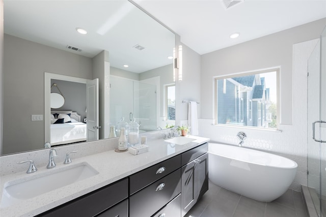 bathroom featuring plus walk in shower, vanity, and tile patterned flooring