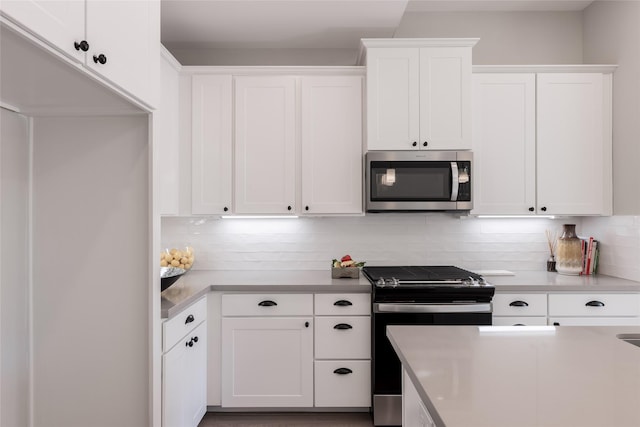 kitchen with tasteful backsplash, white cabinets, and stainless steel appliances