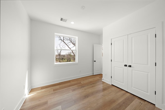 unfurnished bedroom featuring a closet and light wood-type flooring