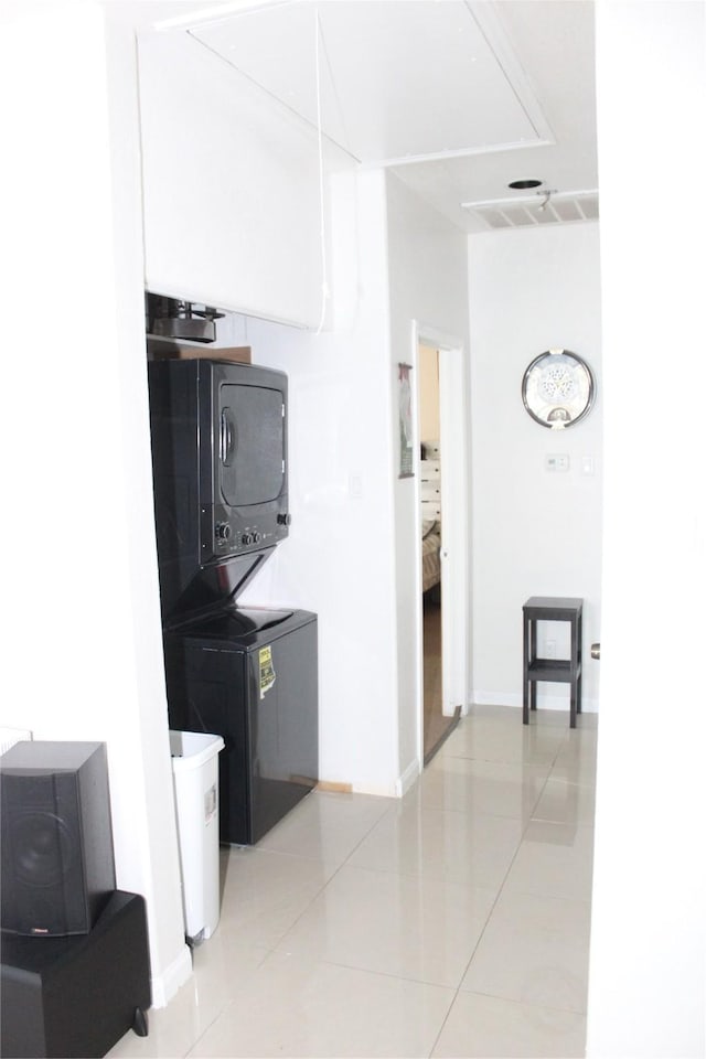 laundry room with stacked washing maching and dryer and light tile patterned floors