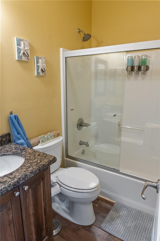 full bathroom with combined bath / shower with glass door, wood-type flooring, vanity, and toilet