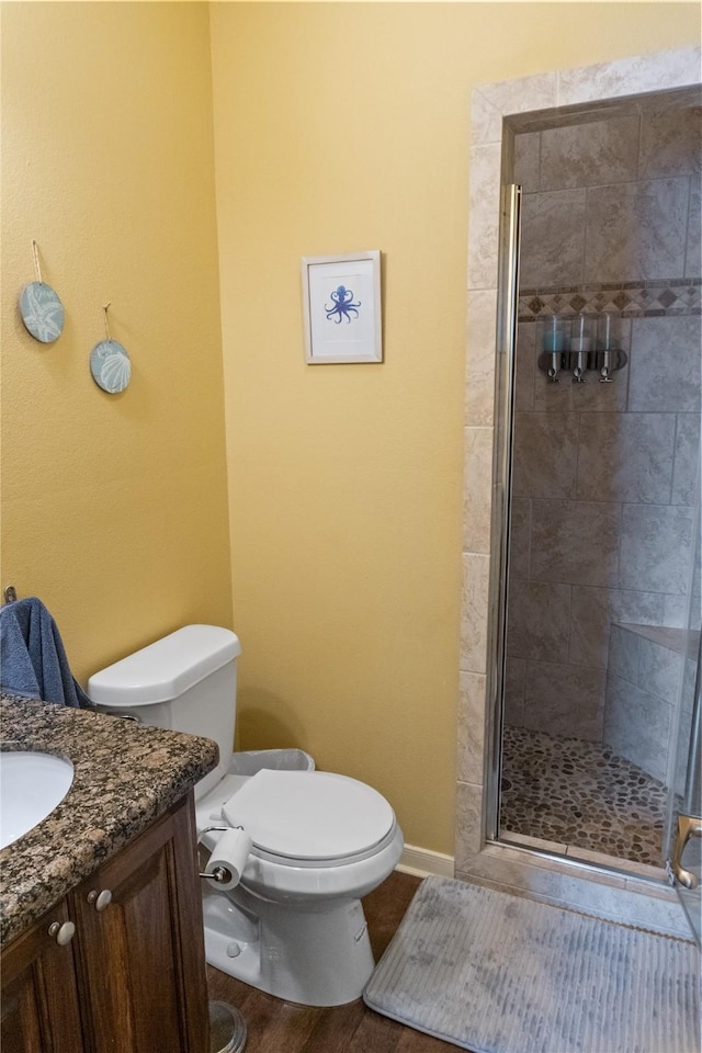 bathroom with wood-type flooring, vanity, toilet, and a shower with shower door