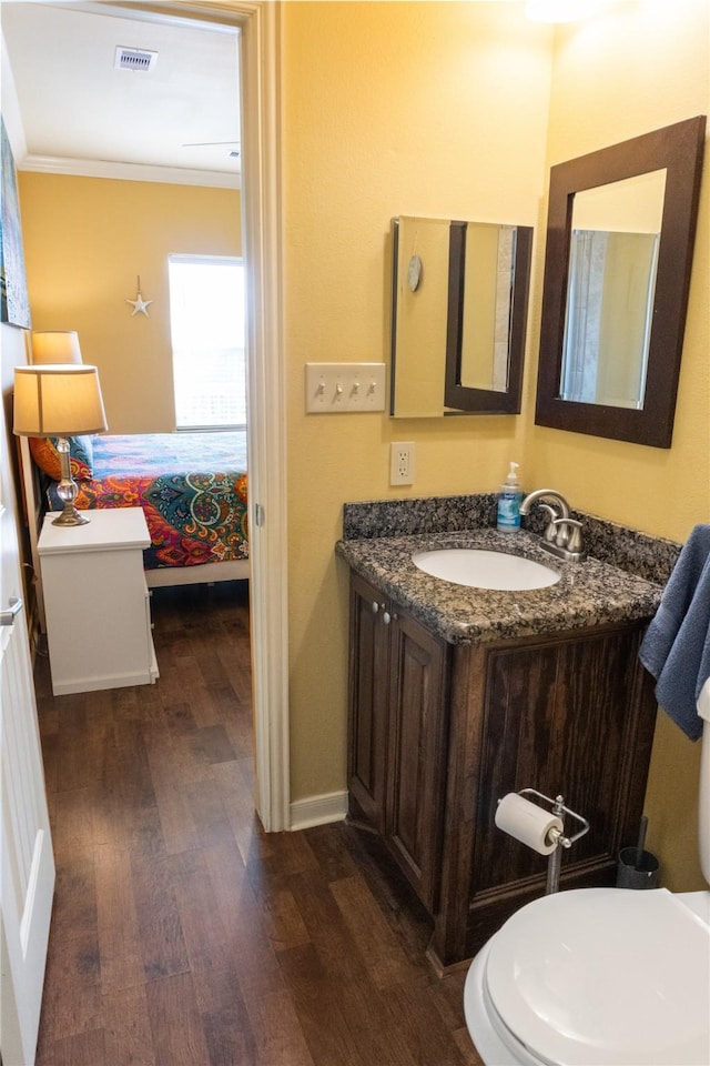 bathroom with hardwood / wood-style flooring, toilet, vanity, and ornamental molding