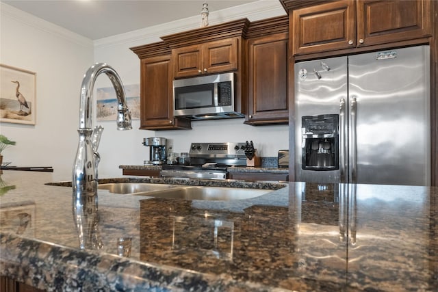 kitchen with sink, dark stone countertops, crown molding, and stainless steel appliances