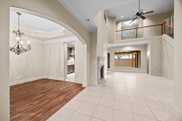 tiled foyer featuring a tile fireplace, crown molding, and ceiling fan with notable chandelier