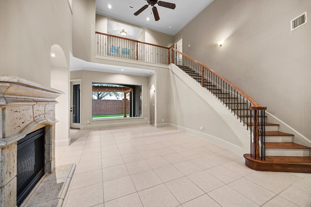 entryway with ceiling fan, a towering ceiling, light tile patterned floors, and ornamental molding