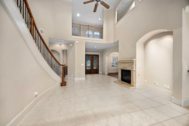 tiled foyer with french doors, ceiling fan, ornamental molding, and a high ceiling