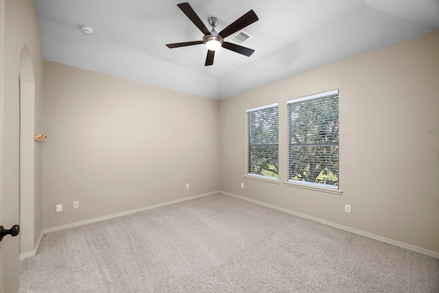 empty room with a tray ceiling, ceiling fan, and light colored carpet