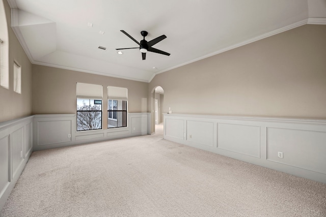 empty room featuring light carpet, vaulted ceiling, ceiling fan, and ornamental molding