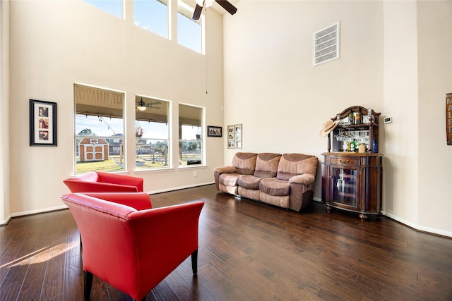 living room featuring ceiling fan, dark hardwood / wood-style flooring, and a towering ceiling