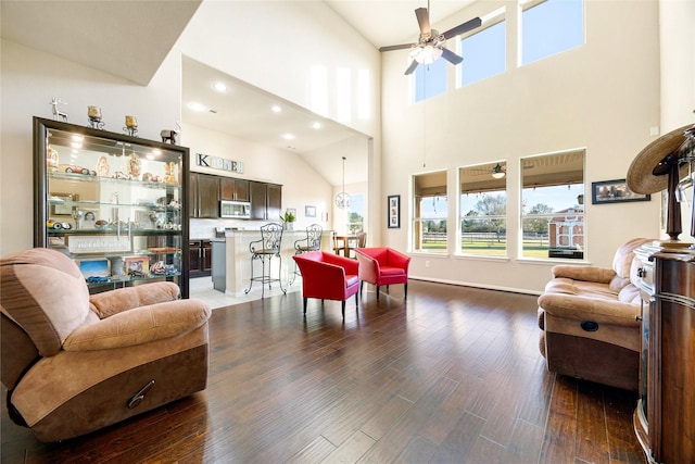 living room featuring ceiling fan, dark wood-type flooring, and a high ceiling