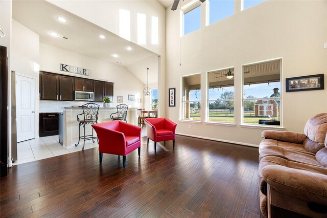 living room featuring ceiling fan, light wood-type flooring, and a high ceiling