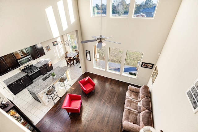 living room featuring ceiling fan, a high ceiling, a wealth of natural light, and hardwood / wood-style floors