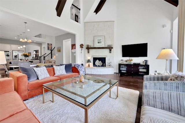 living room with hardwood / wood-style floors, a fireplace, a high ceiling, and an inviting chandelier