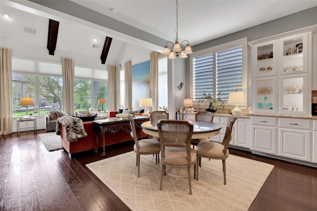 dining space featuring lofted ceiling with beams, a chandelier, and dark hardwood / wood-style floors