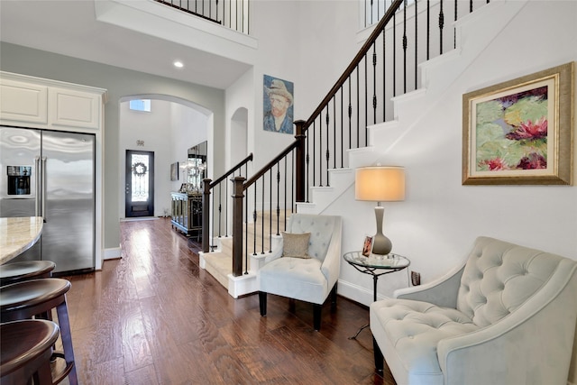 entryway with a towering ceiling and dark wood-type flooring