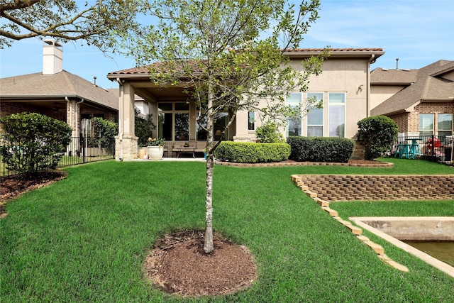 rear view of house featuring a lawn and a patio