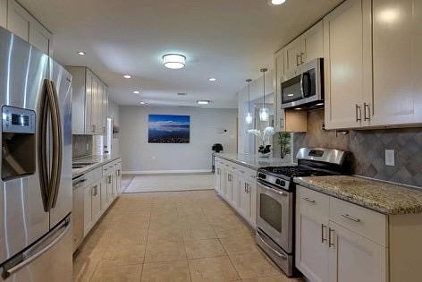 kitchen with decorative light fixtures, light stone countertops, white cabinetry, and stainless steel appliances