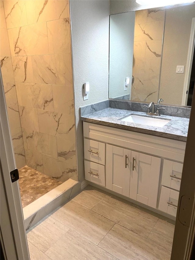 bathroom with vanity and a tile shower