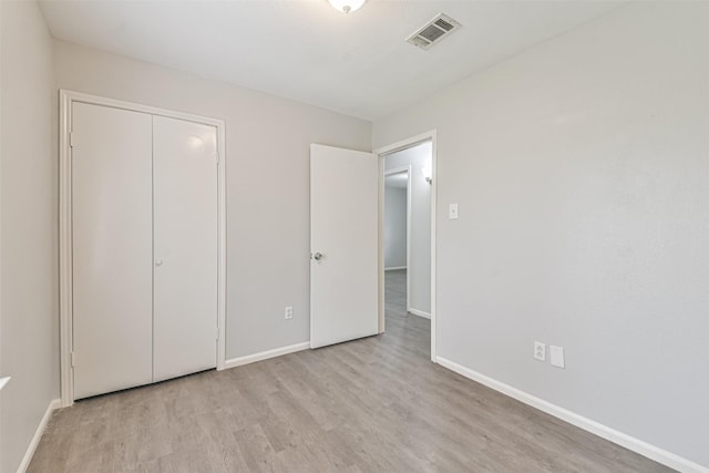 unfurnished bedroom with a closet and light wood-type flooring