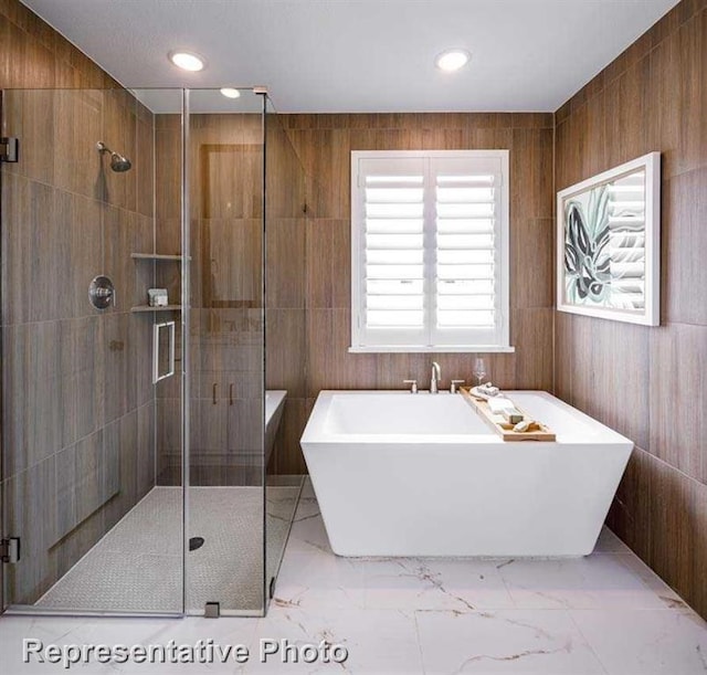 full bathroom featuring recessed lighting, a soaking tub, marble finish floor, and a stall shower