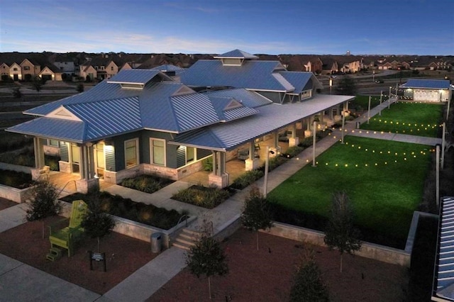 exterior space with a patio, a front lawn, a residential view, and metal roof