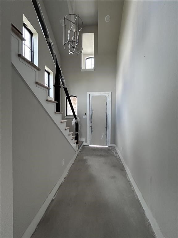 interior space featuring stairs, a towering ceiling, baseboards, and a wealth of natural light