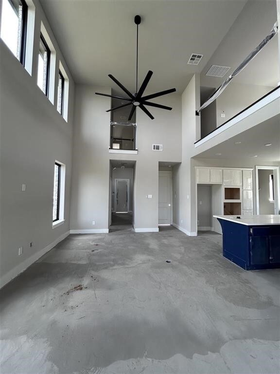 unfurnished living room with a high ceiling, baseboards, and visible vents