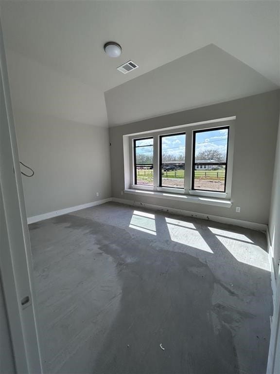 empty room featuring visible vents, unfinished concrete floors, baseboards, and vaulted ceiling