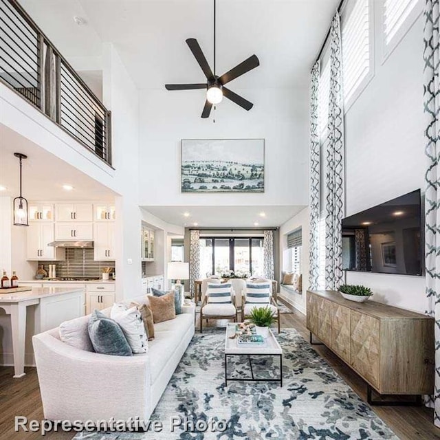 living room with dark wood finished floors, a high ceiling, and ceiling fan