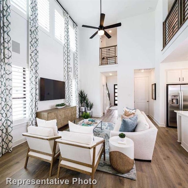 living area with baseboards, stairs, a ceiling fan, and wood finished floors