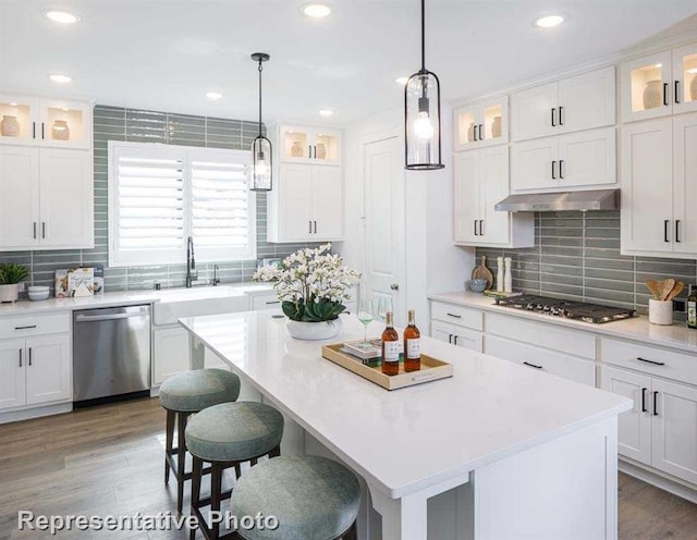 kitchen with under cabinet range hood, white cabinets, stainless steel appliances, and a sink