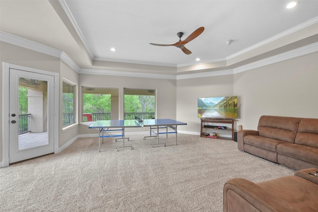 carpeted living room featuring a tray ceiling, ceiling fan, and crown molding