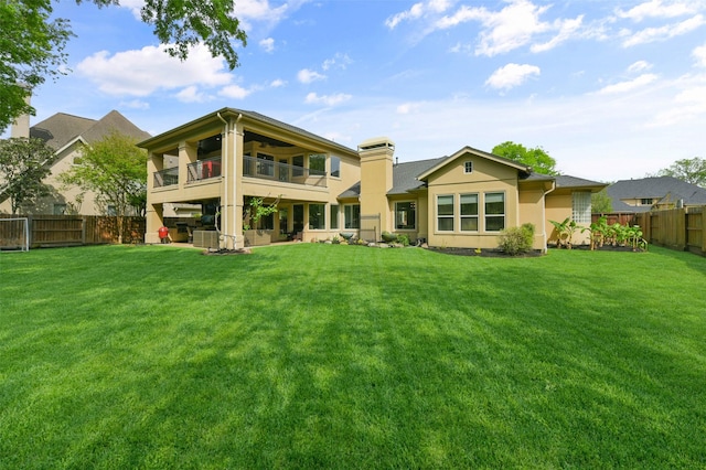 back of house featuring a balcony and a lawn