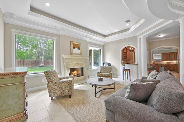 tiled living room featuring a high end fireplace, crown molding, a tray ceiling, and decorative columns