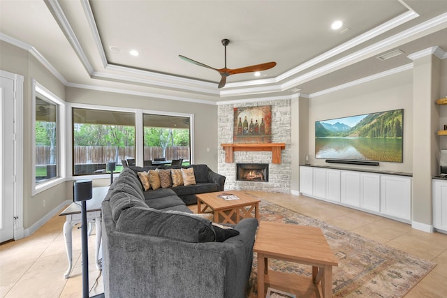 living room featuring a raised ceiling, a fireplace, and ornamental molding