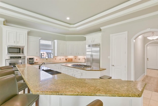 kitchen with a kitchen bar, sink, built in appliances, a large island, and light tile patterned flooring