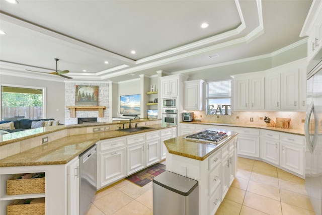 kitchen featuring a raised ceiling, built in appliances, white cabinetry, and a center island