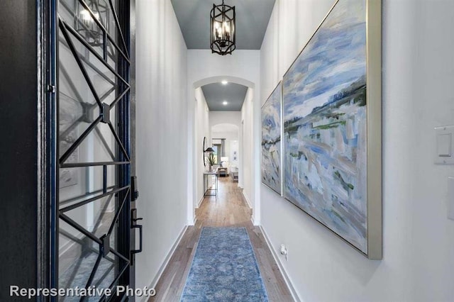 corridor featuring an inviting chandelier and wood-type flooring