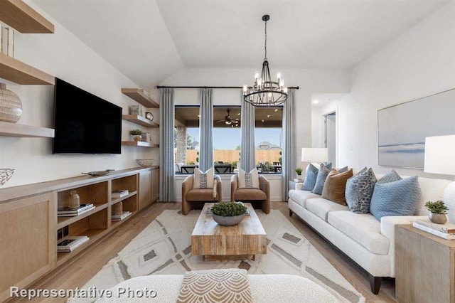 living room featuring a notable chandelier, lofted ceiling, and light wood-type flooring