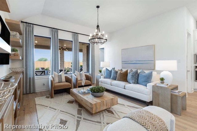 living room featuring lofted ceiling, a chandelier, and light hardwood / wood-style floors