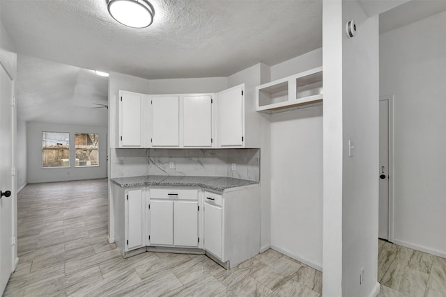 kitchen featuring decorative backsplash, white cabinetry, ceiling fan, and light stone countertops