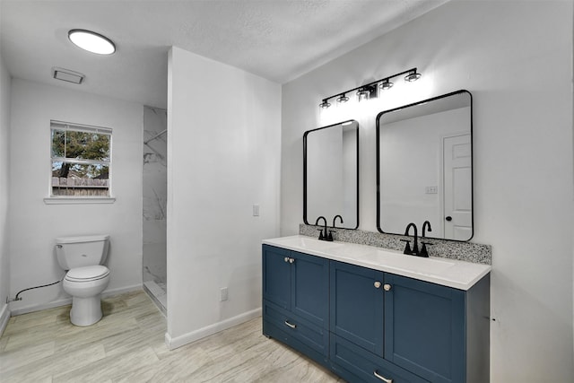 bathroom featuring a shower, vanity, a textured ceiling, and toilet