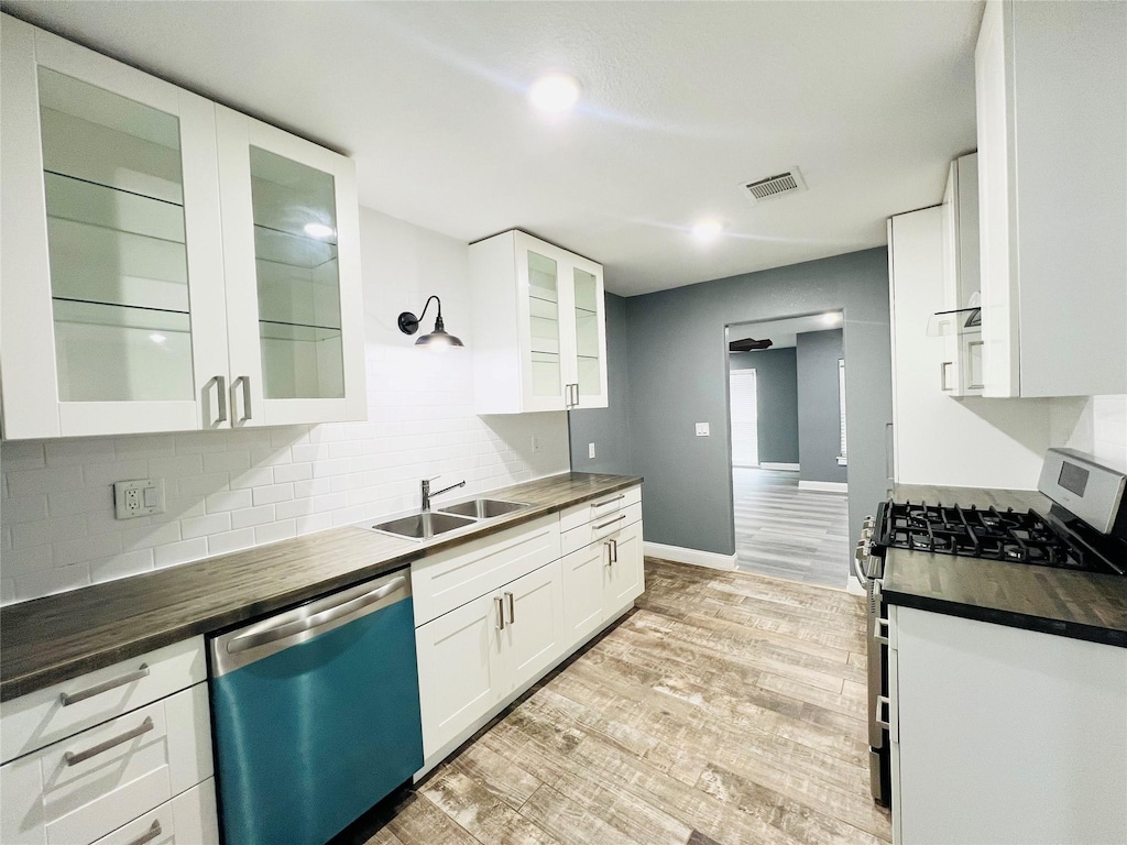 kitchen featuring butcher block counters, white cabinetry, sink, light hardwood / wood-style flooring, and appliances with stainless steel finishes