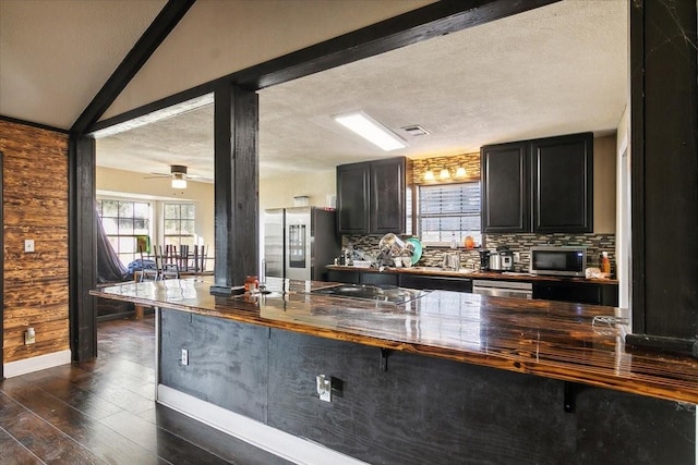 kitchen featuring dark wood-type flooring, ceiling fan, a textured ceiling, tasteful backsplash, and stainless steel appliances