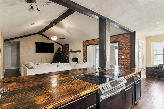 kitchen featuring ceiling fan, dark wood-type flooring, lofted ceiling with beams, a textured ceiling, and electric stove