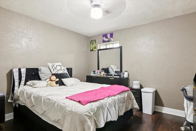 bedroom with ceiling fan, dark wood-type flooring, and a textured ceiling