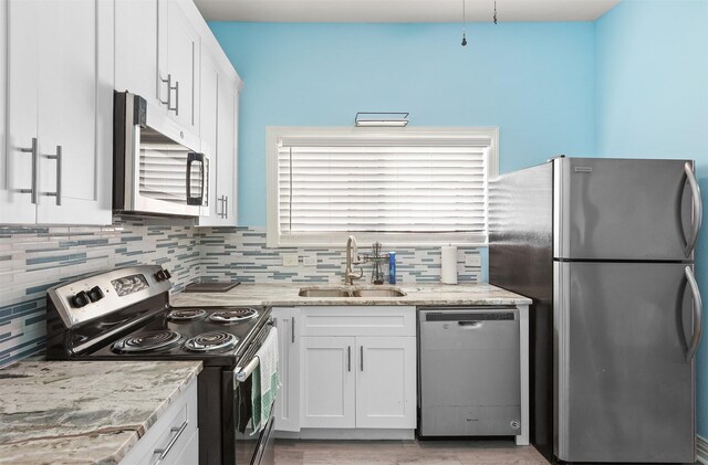 kitchen with light stone counters, sink, white cabinetry, and stainless steel appliances