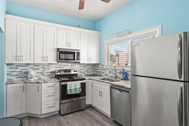 kitchen with light stone countertops, sink, white cabinets, and stainless steel appliances